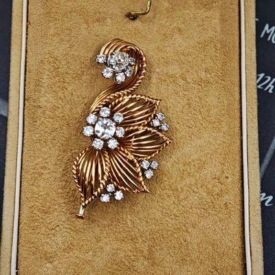 une photo d'une broche en or et diamants dans un écrin