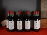 six bottles of red wine are lined up on a table