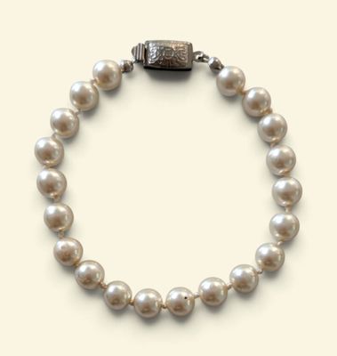 un gros plan sur un bracelet de perles blanches muni d'un fermoir en argent