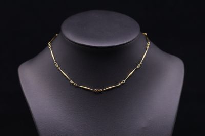 a gold necklace on a mannequin with a black background
