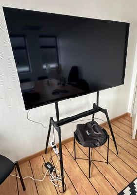 un téléviseur à écran plat posé sur un support dans le coin d'une pièce