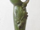 a green vase with a bird on top of it