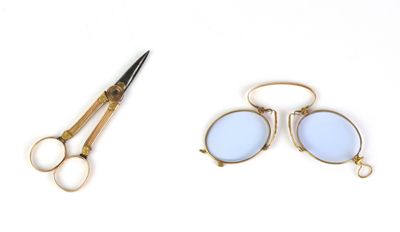 une paire de ciseaux et une paire de lunettes posés sur une surface blanche