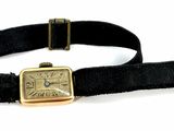 a watch that is on a black strap with a gold buckle