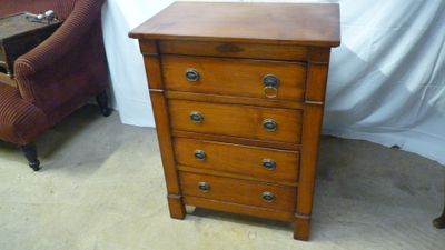 une petite commode en bois dans un coin de la pièce
