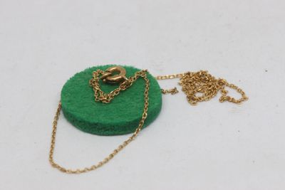 necklace with a gold chain and a green felt disc on a white surface