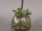 a green vase with a stick sticking out of it