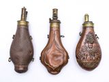 trois bouteilles anciennes plaquées laiton sont alignées sur un fond blanc