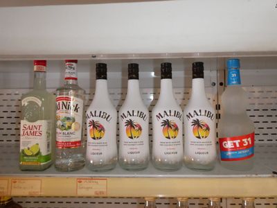 Des bouteilles d'alcool sont alignées sur une étagère dans un magasin