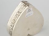a silver heart shaped box on a white surface