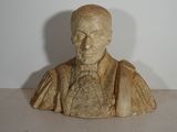 statue représentant le buste d'un homme en costume-cravate, posée sur une table