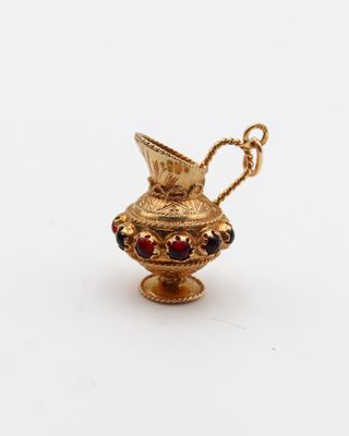 une image représentant un petit vase en or orné d'une perle rouge et verte