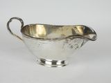 une saucière ancienne en métal argenté, dotée d'une poignée incurvée