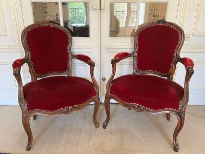 pair of red velvet upholstered chairs in front of a white door