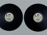 two black vinyl records sitting on top of a white surface