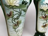 two vases with flowers painted on them sitting on a table