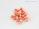 a close up of a bunch of coral beads on a white surface