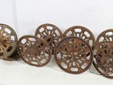 six antique cast iron wheels are lined up on a white surface