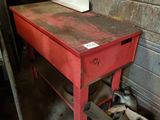 une table rouge sur laquelle se trouve une boîte, dans une pièce