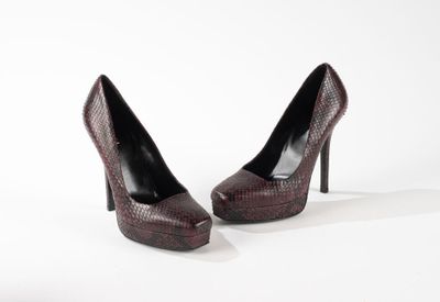 une paire d'escarpins en peau de serpent marron posés sur une surface blanche