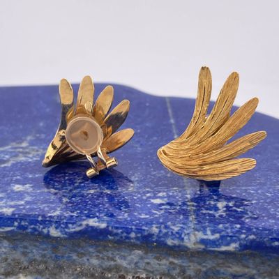 pair of gold plated flower earrings on a blue marble slab