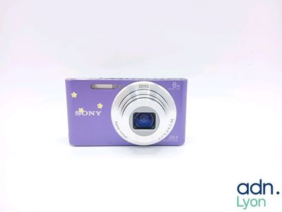 purple digital camera sitting on a white surface with a white background