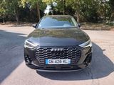 the front of a black audi suv parked on the side of the road