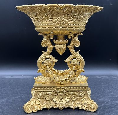 un vase en or richement décoré, posé sur un socle, sur fond noir