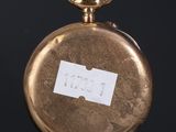a gold pocket watch with a note on it