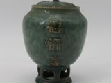 a green vase with writing on it sitting on a table