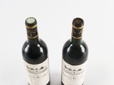 two bottles of wine sitting next to each other on a white surface