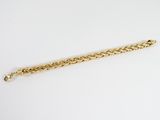 gros plan d'un bracelet en or sur une surface blanche
