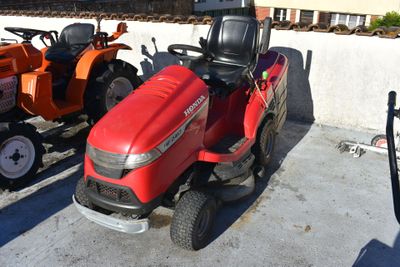 two lawn mowers parked next to each other in a parking lot