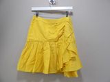 yellow skirt hanging on a hanger against a wall
