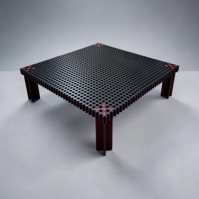une table noire parsemée de points rouges, posée sur une surface blanche