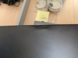 a black laptop computer sitting on a desk with a yellow sticker on it