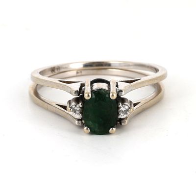gros plan d'une bague avec une pierre verte et des diamants