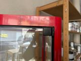a red cabinet with a glass door and a shelf in the background