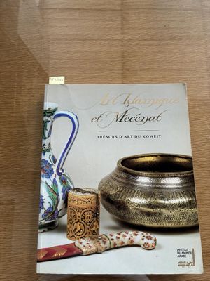 the book is sitting on a table next to a vase and other items