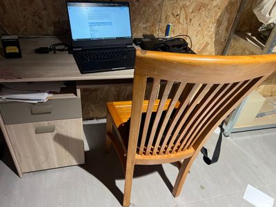 un ordinateur portable posé sur une chaise en bois devant un bureau