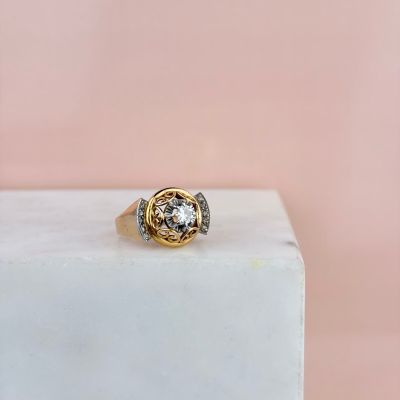une bague en or et diamants posée sur un bloc de marbre blanc