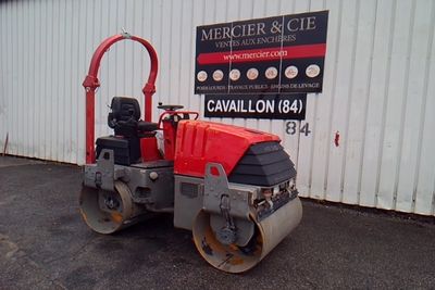 a red and black road roller parked in front of a building
