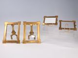 three gold picture frames and a mirror on a white surface
