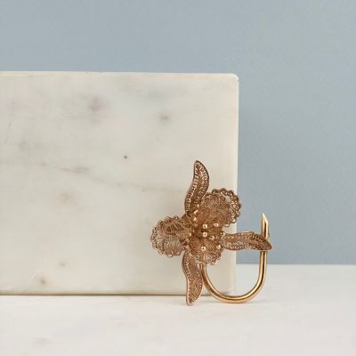 une surface en marbre blanc sur laquelle est fixé un crochet en métal doré