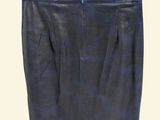 a black leather skirt hanging on a hanger on a white wall