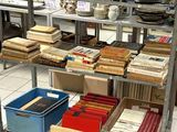 de nombreuses caisses de livres posées sur une étagère dans une pièce
