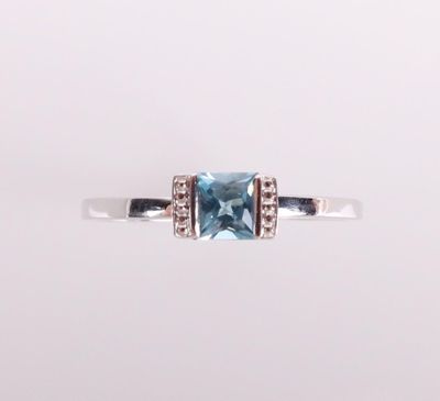 a close up of a ring with a blue topaz stone and diamonds