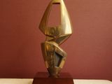 a gold sculpture on a white pedestal against a red wall