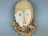 un masque en bois orné d'un nid d'oiseau