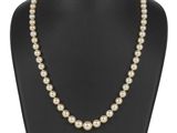 un collier de perles autour du cou d'un mannequin, muni d'un fermoir en or
